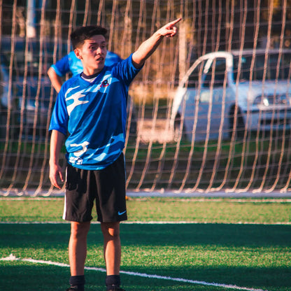 Teen in blue sports jersey pointing on a soccer field
