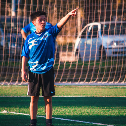 Teen in blue sports jersey pointing on a soccer field